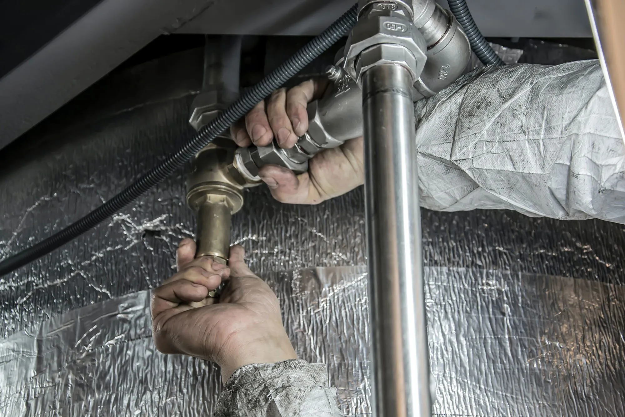 Plumber hands installing or repairing metal pipes.
