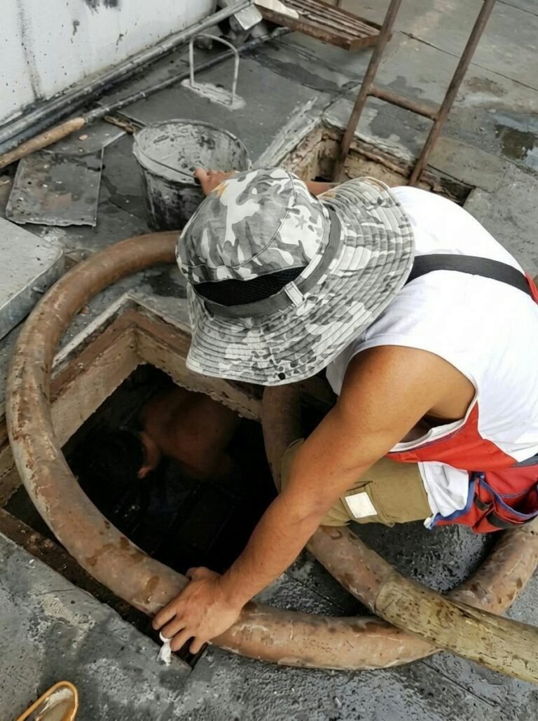 JA Torres crew member checking an open septic tank manhole before siphoning