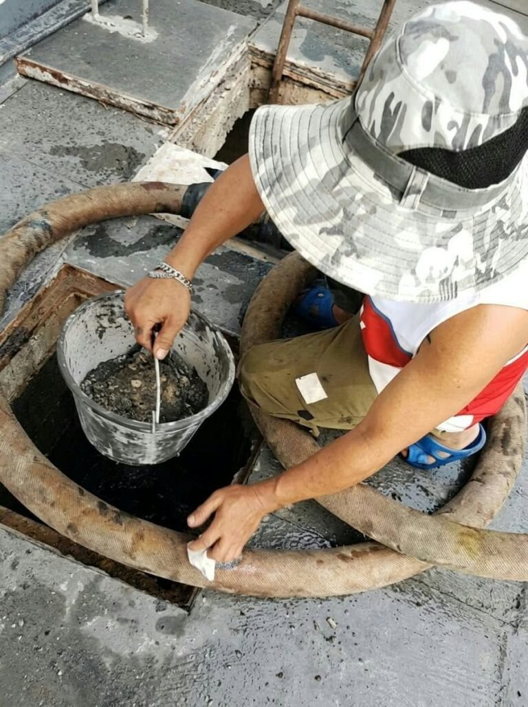 JA Torres crew member removing sludge from a septic tank by hand