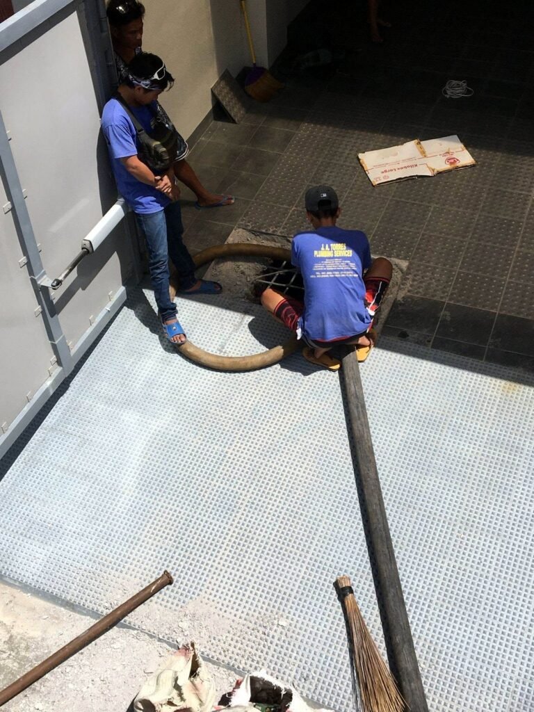 JA Torres crew siphoning a septic tank through a floor opening at a commercial property