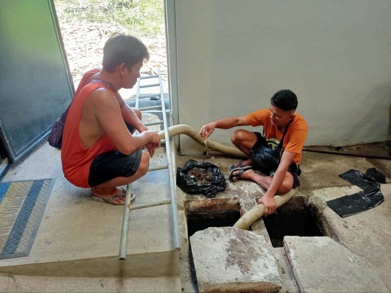Two JA Torres crew members siphoning a septic tank at a building entrance