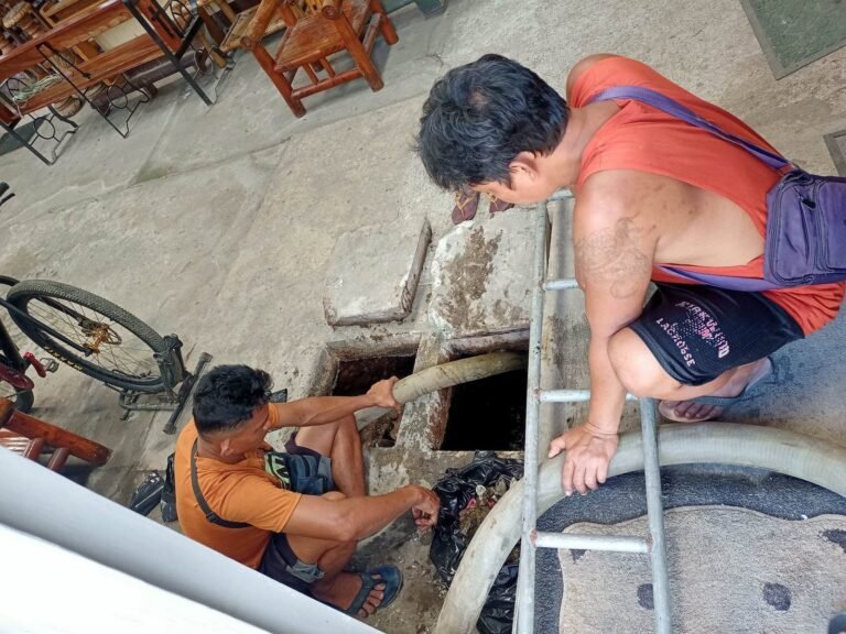 JA Torres crew siphoning a septic tank with a ladder and vacuum hose
