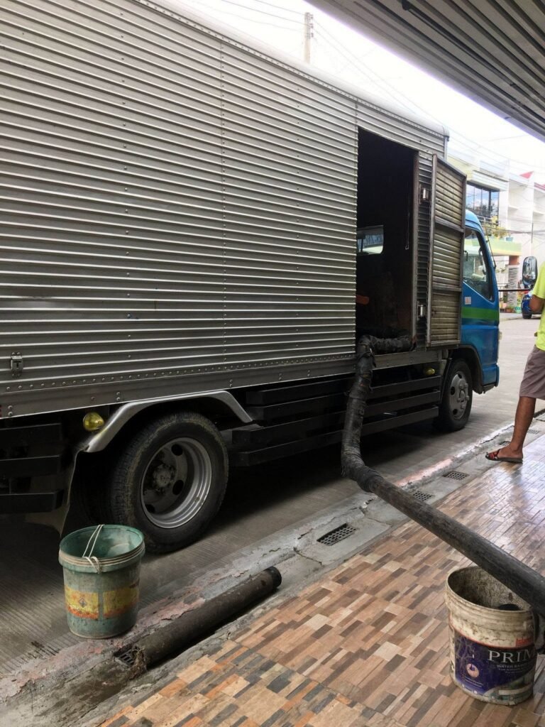 JA Torres siphoning truck parked curbside with hose laid out for a septic job